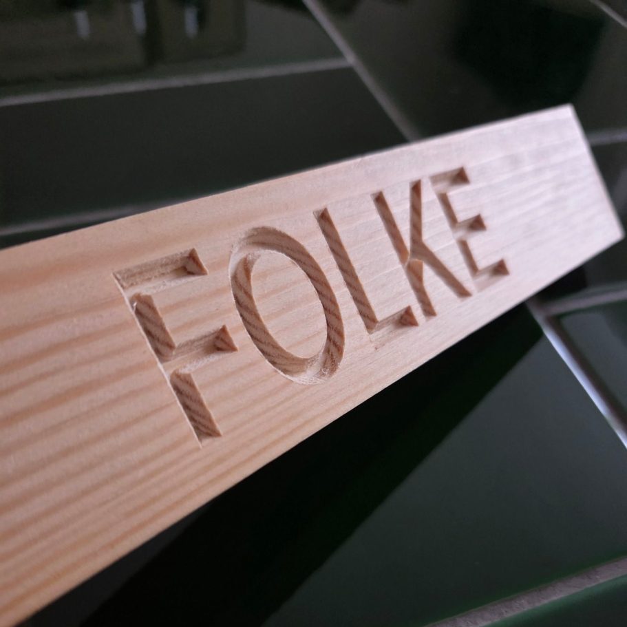 Träbit med inskriptionen "FOLKE" i djup relief.